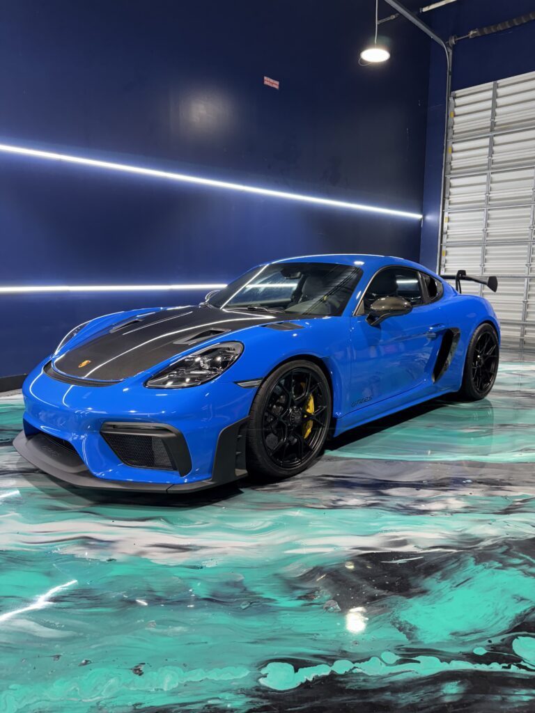 Porsche 718 Cayman GT4 RS with full paint protection film (PPF) applied, showcased in a studio under bright lighting