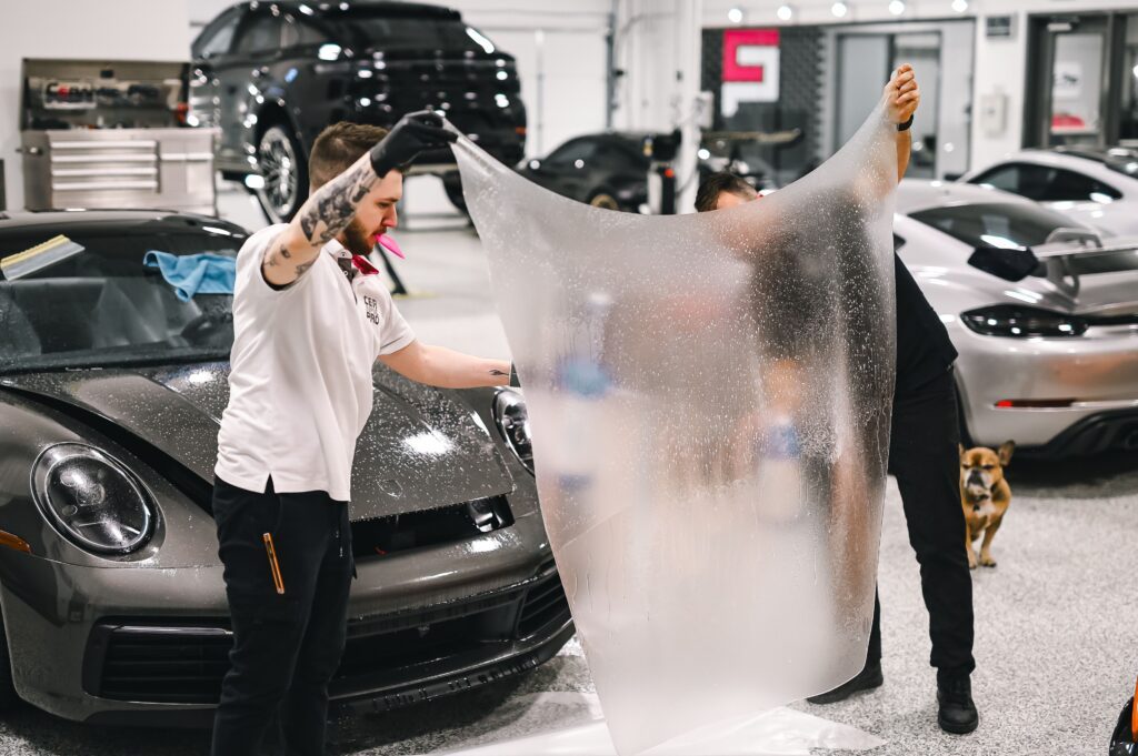 Professional Paint Protection Film (PPF) installation on a luxury sports car at a premium vehicle protection shop in Orlando, Florida.